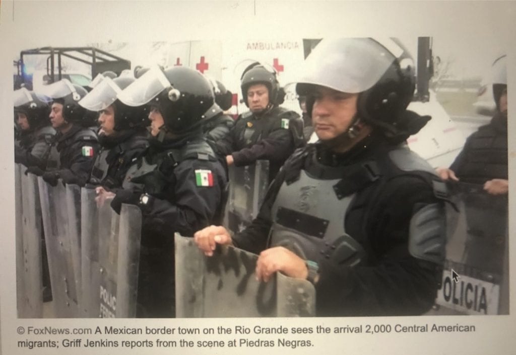 Police in riot gear with shields standing.